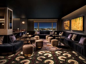 Een moderne lounge met een bar, zitplaatsen en uitzicht op de stad.