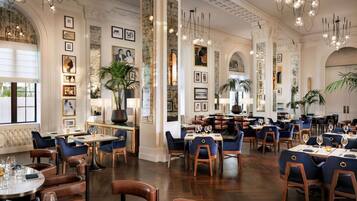 Um restaurante espaçoso com tetos altos, lustres e decoração clássica.