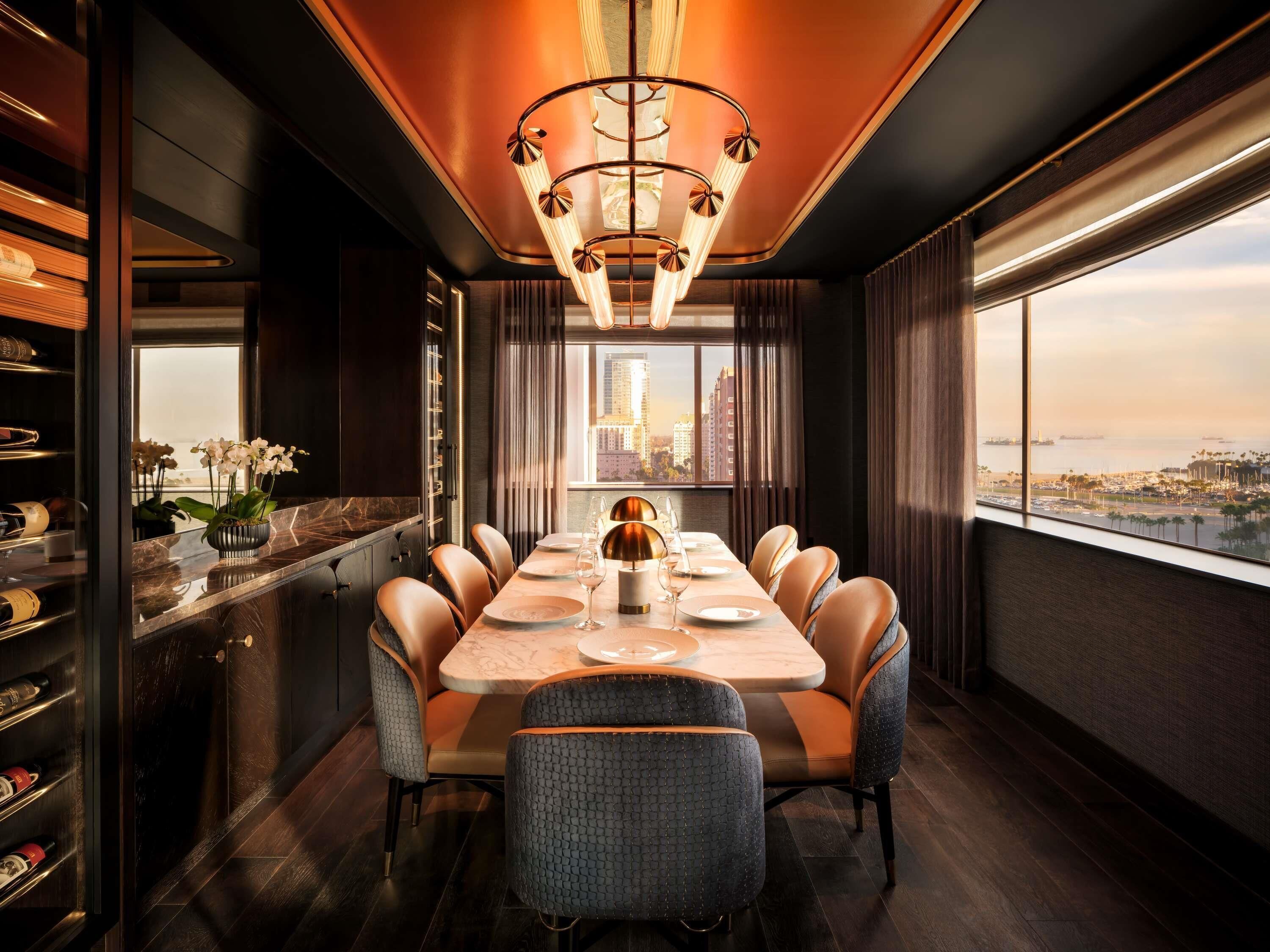 A dining area with a city view, a chandelier, and a wine rack.