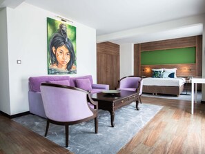 A modern bedroom with a bed, a green wall, a painting, and a purple sofa. - Ibis Styles Cayenne Centre Amazonia (Ouverture Juin 2024) (Cayenne)