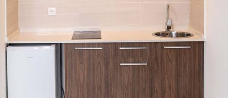 Una cocina compacta con lavavajillas integrado, un lavamanos de acero inoxidable y armarios de madera.