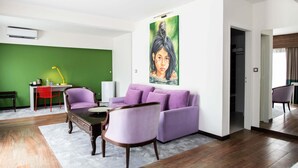 Una sala moderna con una pared de acento verde, un conjunto de sofá morado, una mesa de centro de madera y un cuadro en la pared.