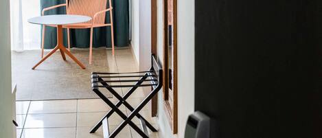 Une pièce comprenant une chaise pliante noire, une petite table ronde et une chaise dont le dossier est en osier tressé.