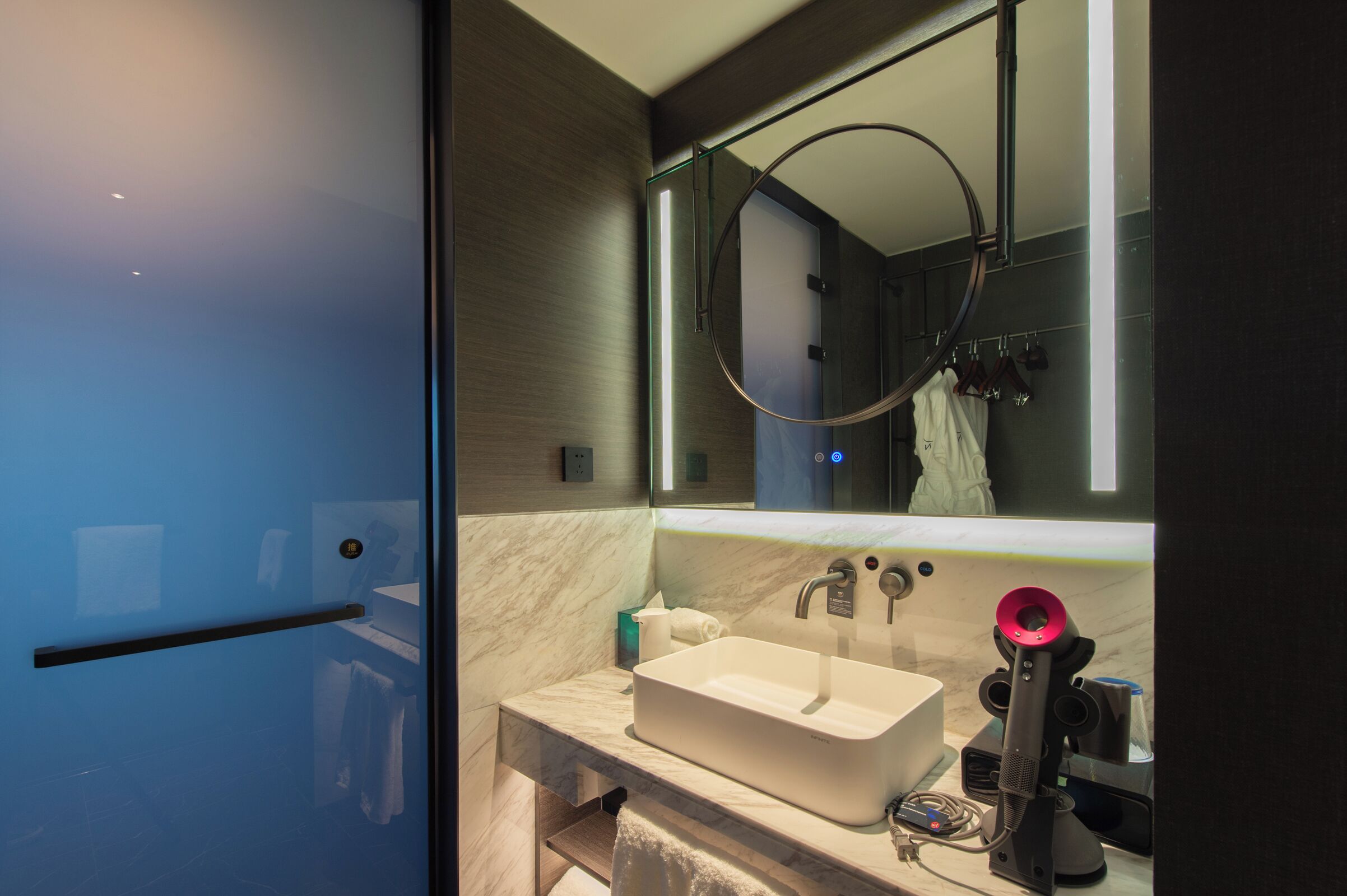 Een moderne badkamer met een grote spiegel, een wastafel en een handdoekhouder.