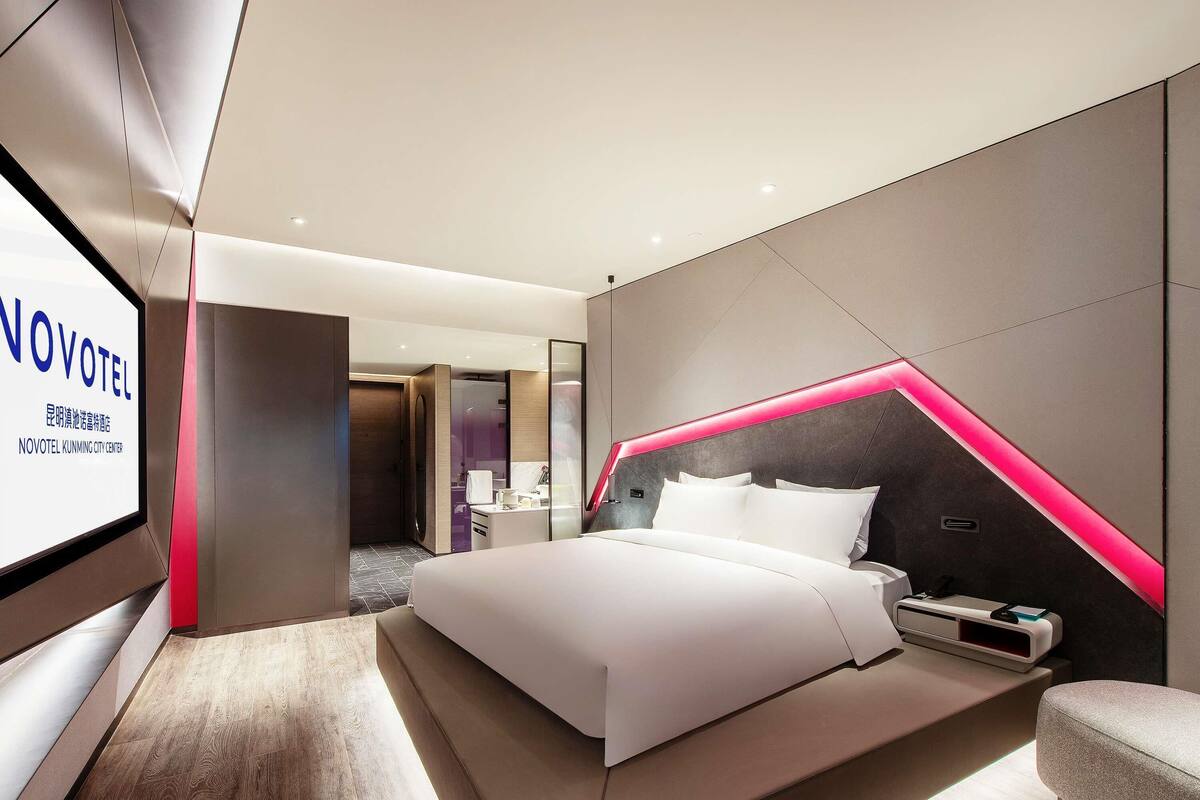 Una habitación de hotel moderna con cama, mesita de noche y un espejo grande.