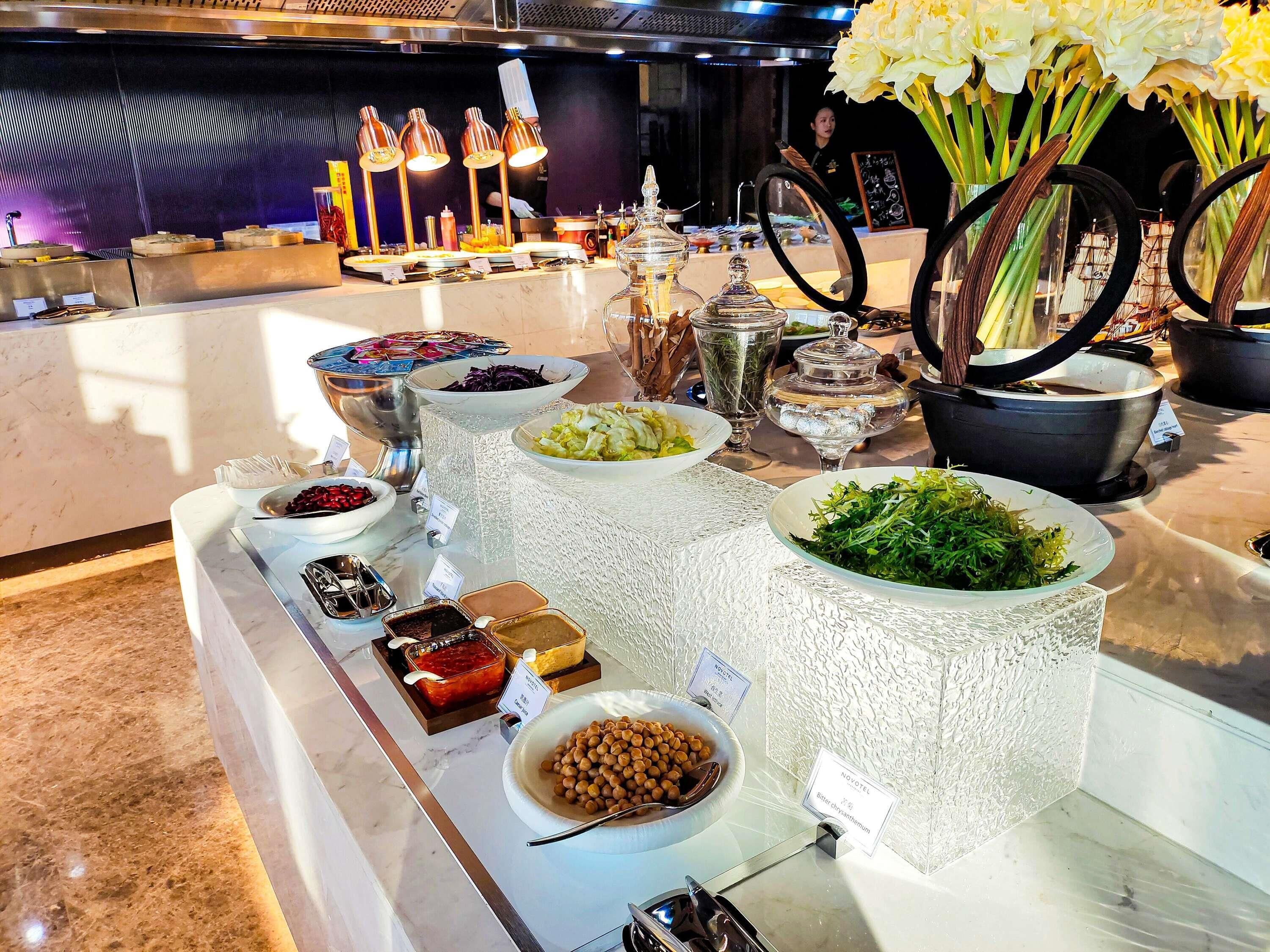 Een buffet met diverse gerechten en toevoegingen, waaronder een kom kikkererwten en een bakje yoghurt.