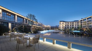 A riverside terrace with outdoor seating and modern buildings in the background. - Pullman Taizhou Shenxianju (Taizhou)