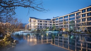 A modern hotel with a reflective pool, large windows, and a moon in the sky. - Pullman Taizhou Shenxianju  (Taizhou)