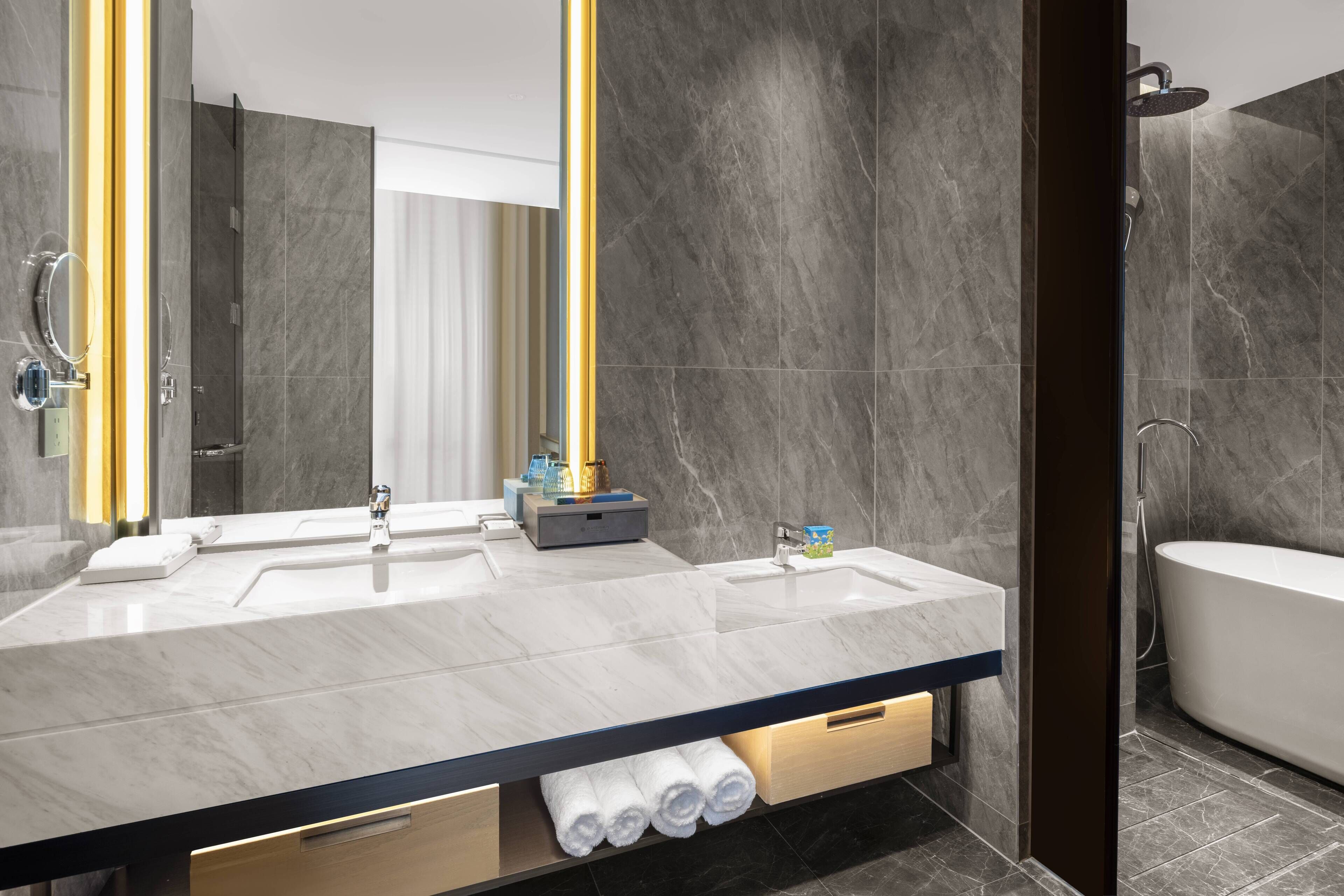 Un baño moderno con un tocador espacioso, lavamanos dobles, un espejo y una bañera.
