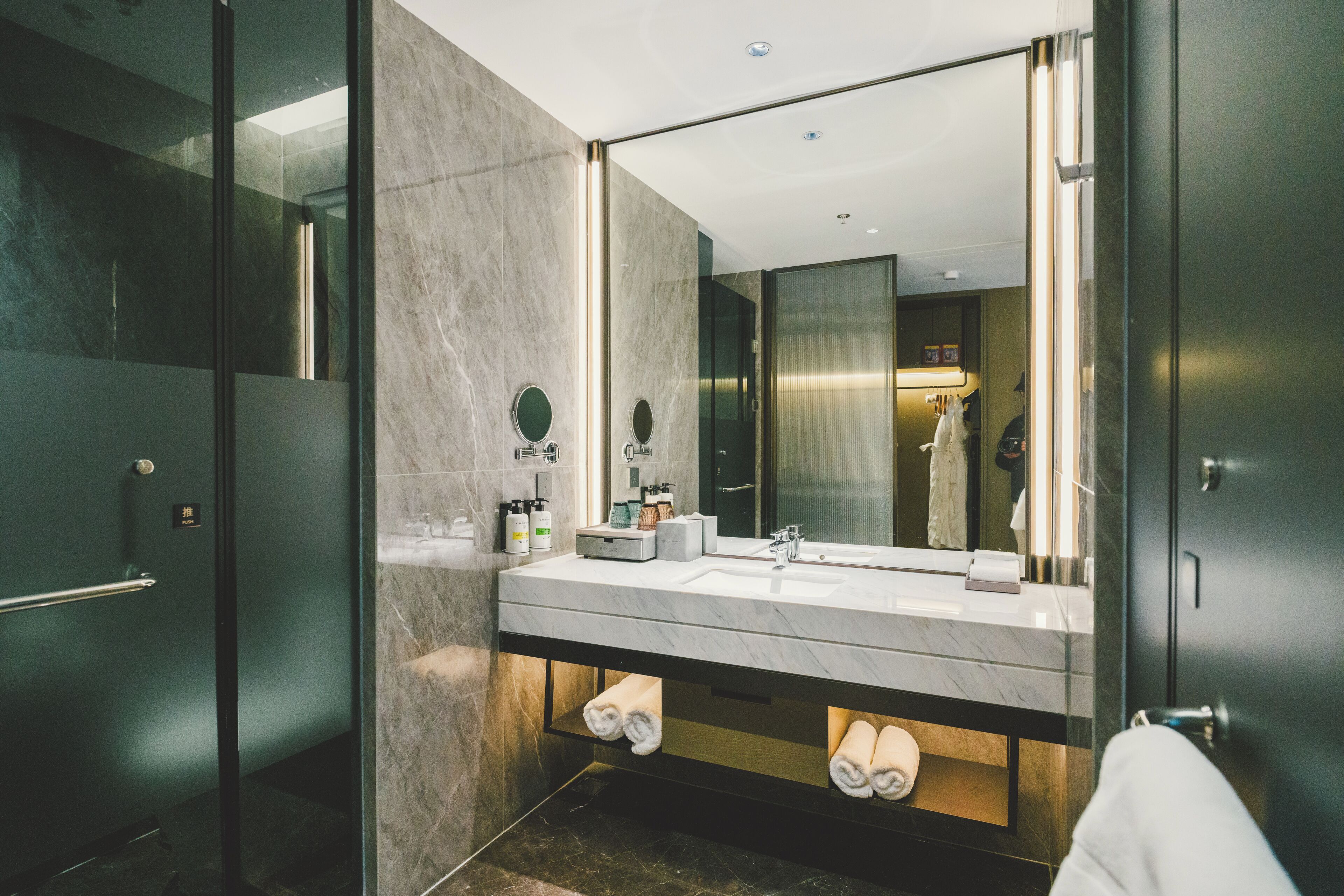 Une salle de bain moderne dotée d’un grand miroir, de deux vasques et d’une douche à parois de verre.