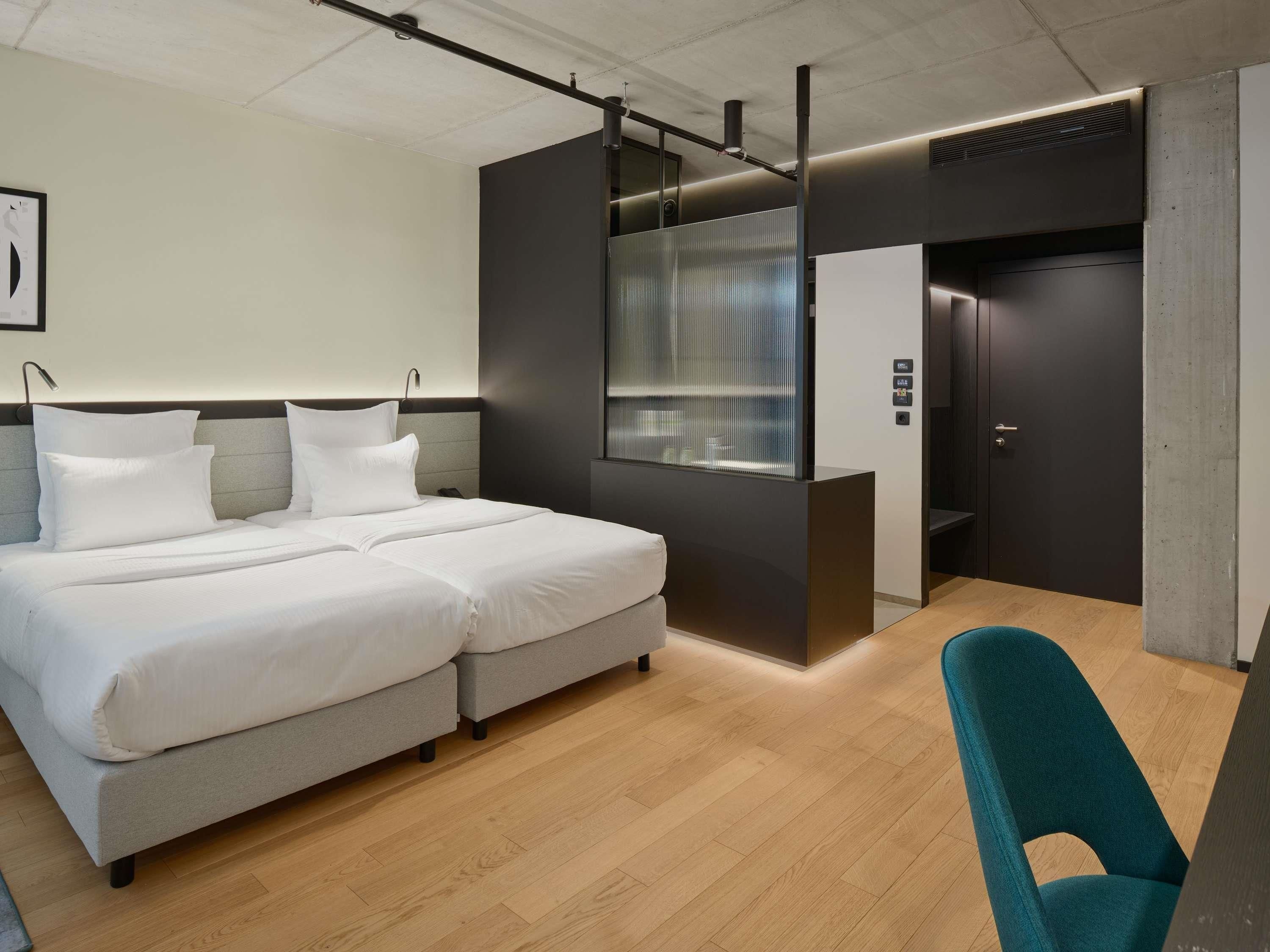 Une chambre d’hôtel moderne avec un grand lit, un bureau et une armoire.