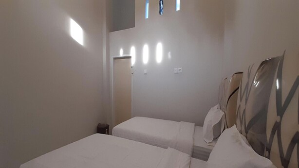 A hotel room with two beds, a small table, and a window with blinds. - Hotel O Gurita Residence Syariah (Padang)
