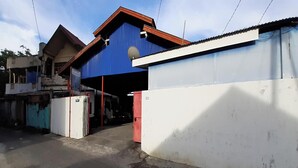 A building with a blue and white exterior, a red door, and a visible satellite dish. - Hotel O Gurita Residence Syariah (Padang)