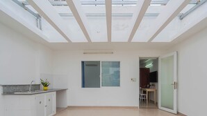 A spacious room with a skylight, a kitchen area with cabinets and a sink, and a door leading to another room. - LaLaHouse Riverside Residence (Ho Chi Minh City)