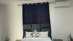 Un dormitorio moderno con una cama grande, cortinas oscuras y un ventilador de techo.