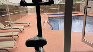 Ein Fitnessrad in einem Raum mit Glaswand und Blick auf einen Pool.