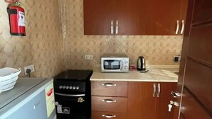 Una cocina compacta con microondas, estufa y armarios.