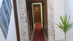 A hallway with a red carpet leading to a door with a decorative archway. - LUNA HOTEL (Cairo)