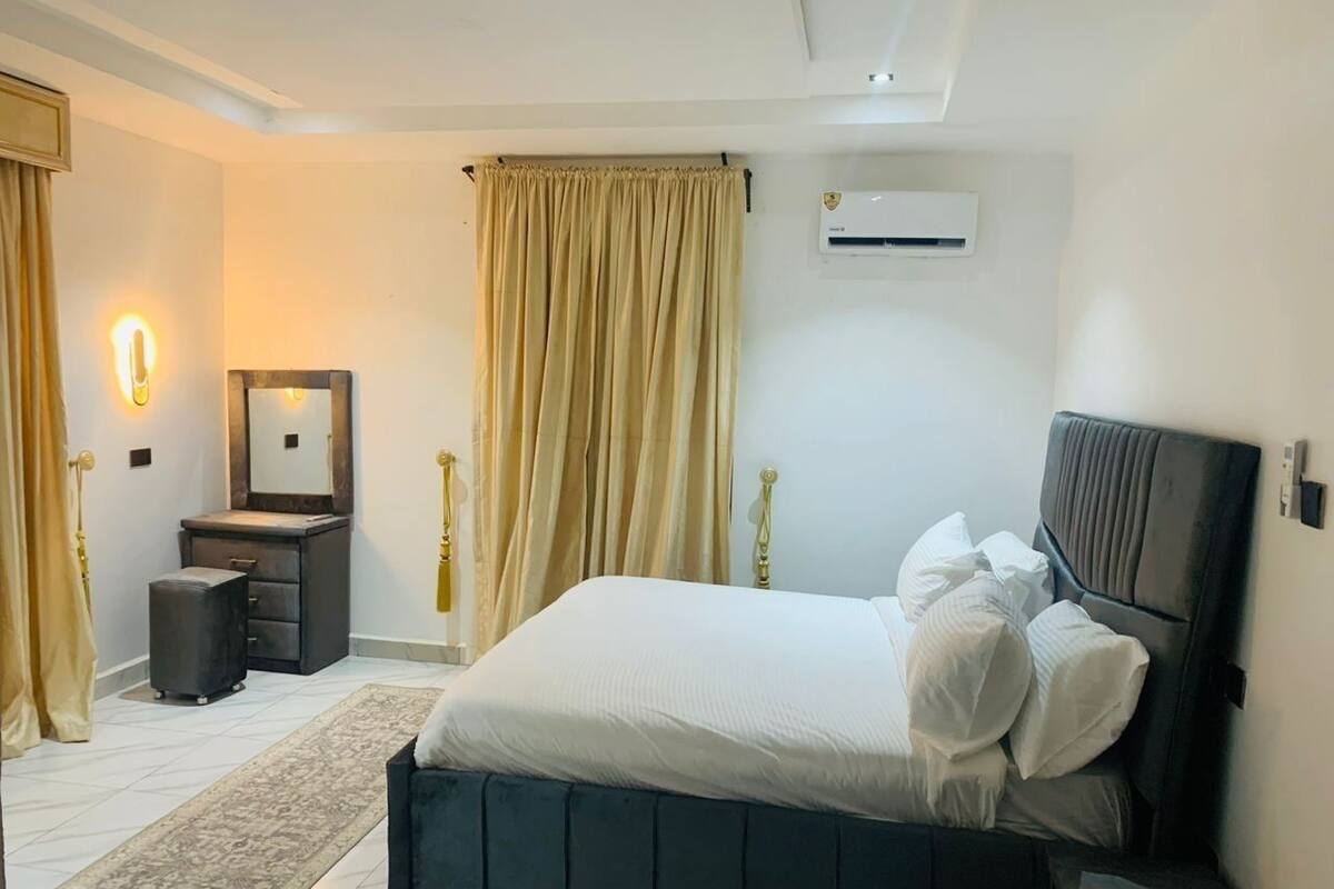 Un dormitorio moderno con una cama grande, una mesita de noche, un espejo y un equipo de aire acondicionado en la pared.