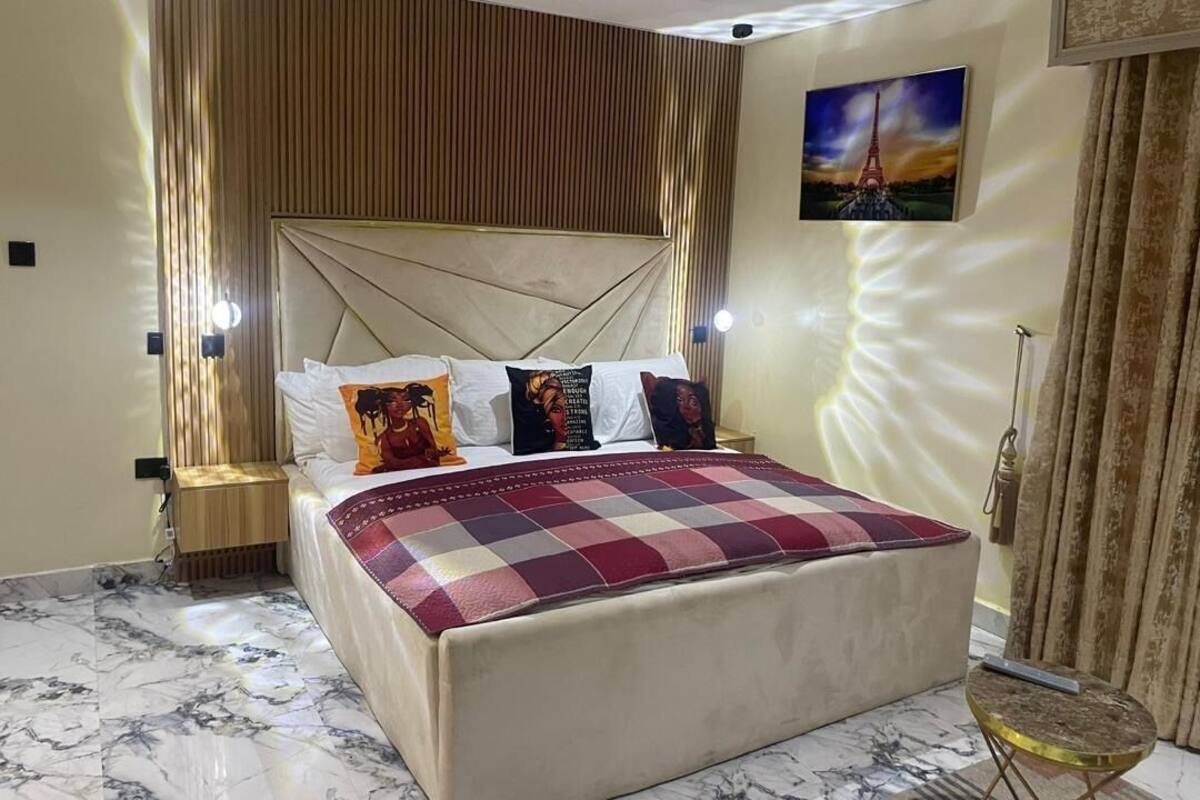 Un dormitorio con una cama grande, un cabecero y una mesita de noche.