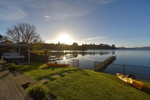 A lakeside property with a hot tub, a kayak, and a wooden deck. - Lakefront Oasis - Jetty, Hot Tub & Kayaks (Okere Falls)