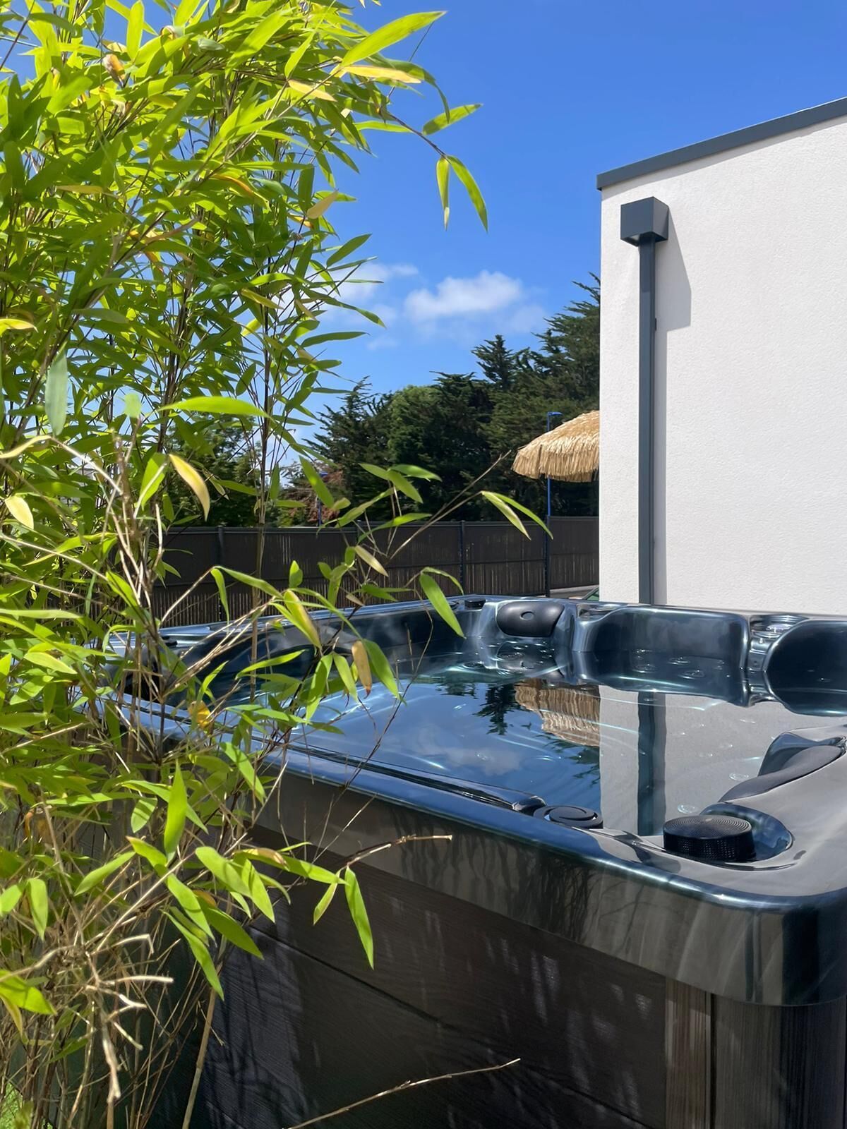 Un bain à remous offrant une vue dégagée sur les environs, notamment sur un bâtiment blanc et une clôture en bois.