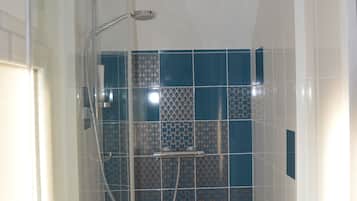 Een douche, handdoeken, zeep, toiletpapier