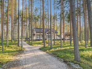 Une cabane au milieu d’une forêt, avec un chemin de gravier qui y mène.
