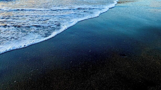 A beach with waves, a distant island, and a clear sky. - Charming Condo Orchidea (Playas Del Coco)