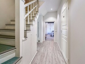 A hallway with a wooden staircase, a door with a handle, and a light switch on the wall. - Holiday pleikilä by Interhome (Kustavi)
