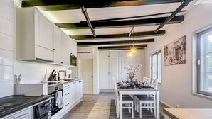 A modern kitchen with white cabinetry, a black countertop, and a dining area with a table and chairs.