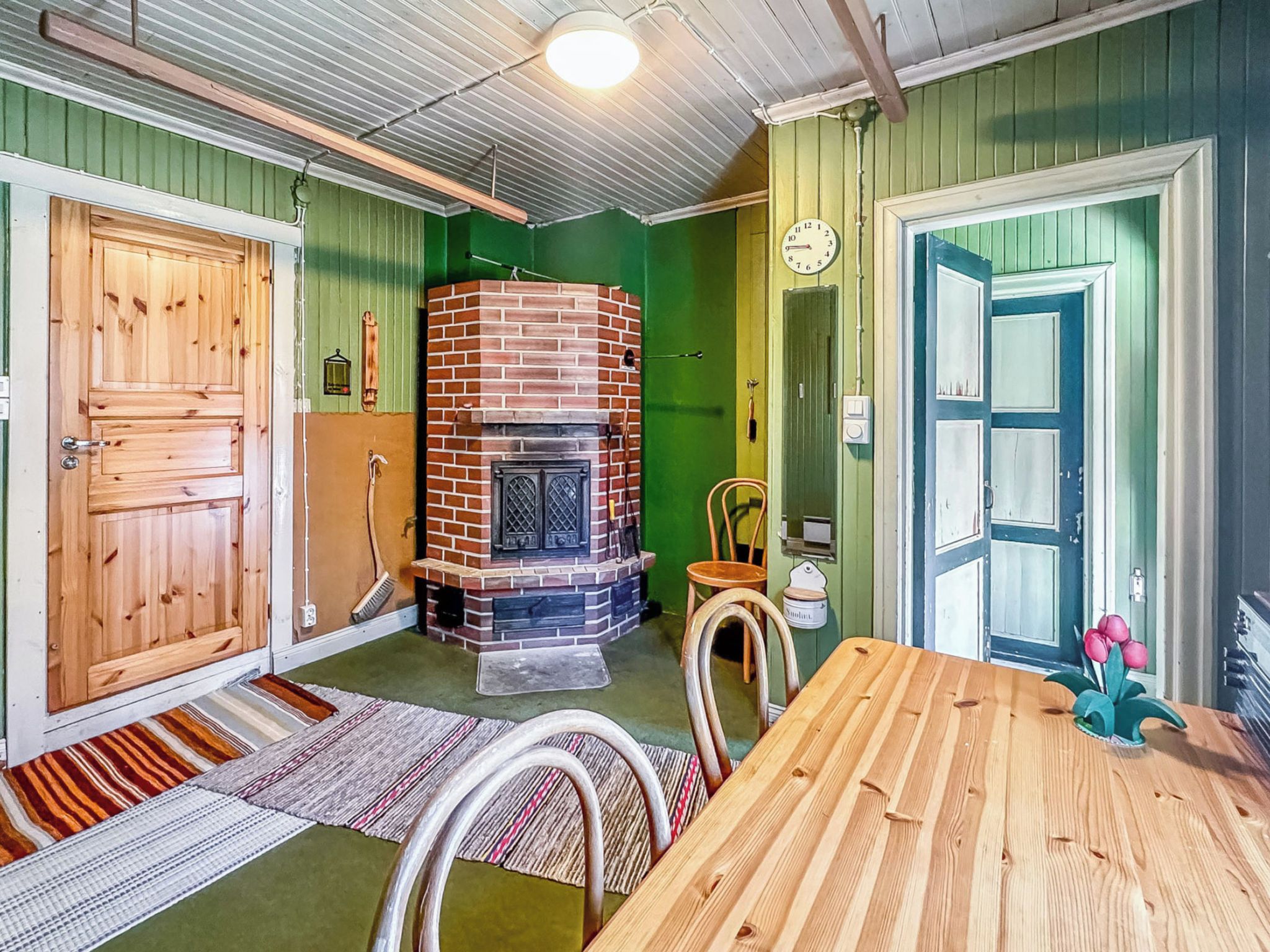 Une pièce avec une cheminée en briques, des portes en bois, une table à manger et un mur vert.