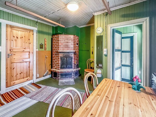 Una habitación con chimenea de ladrillo, puertas de madera, una mesa de comedor y una pared verde.