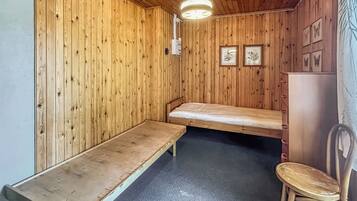 Een kleine, eenvoudige blokhut met houten inrichting, een bank, een stoel en een bed.