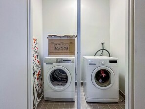 A laundry room with two front-loading washing machines, a drying rack, and a sign above the machines. - Holiday pleikilä by Interhome (Kustavi)