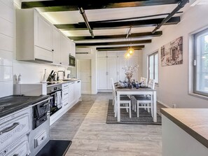 A modern kitchen with white cabinets, a black countertop, and a dining area with a table and chairs. - Holiday pleikilä by Interhome (Kustavi)