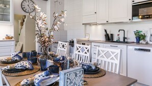 A modern kitchen with white cabinetry, a Bosch oven, and a dining area set with blue and white tableware.