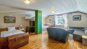 A room with a bed, a green pillar, a sofa, and a window.