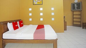 Una cama bien hecha con ropa blanca y roja, un cabecero de madera y una obra de arte colgada en la pared.