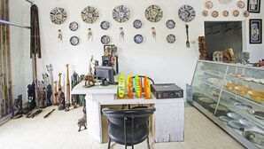 Una habitación con una vitrina de platos y figuritas en la pared, una encimera con varios objetos, y una vitrina de vidrio con más artículos.