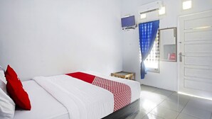 Habitación de hotel con una cama, una mesita de noche, un televisor montado en la pared y una puerta con un letrero.