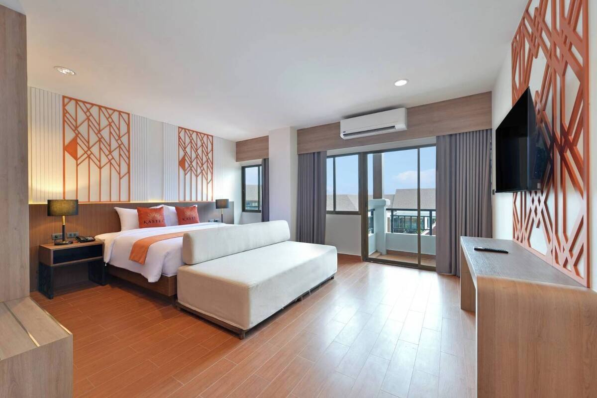 Una habitación de hotel moderna con una cama grande, un escritorio, un televisor y un balcón con vistas.