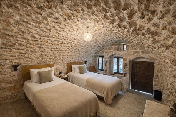 A rustic room with stone walls and two beds.