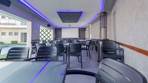 A conference room with tables and chairs, a projector screen, and a ceiling with blue LED lighting. - Botle Ba Afrika Lodge (Vereeniging)