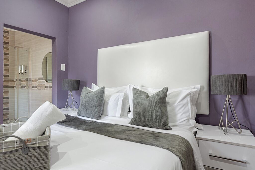 A bedroom with a large bed, a nightstand, a lamp, and a basket.