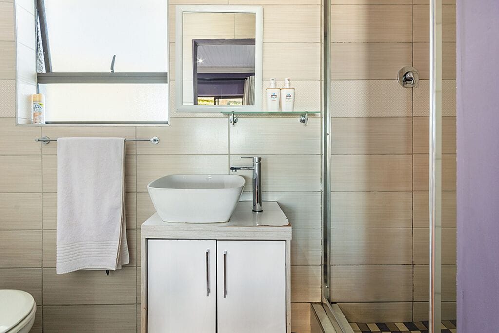Un bagno moderno con un lavandino bianco, uno specchio e una cabina doccia in vetro.