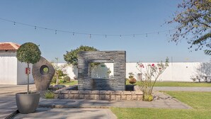A courtyard with a stone structure, potted plants, and a string of lights. - Botle Ba Afrika Lodge (Vereeniging)