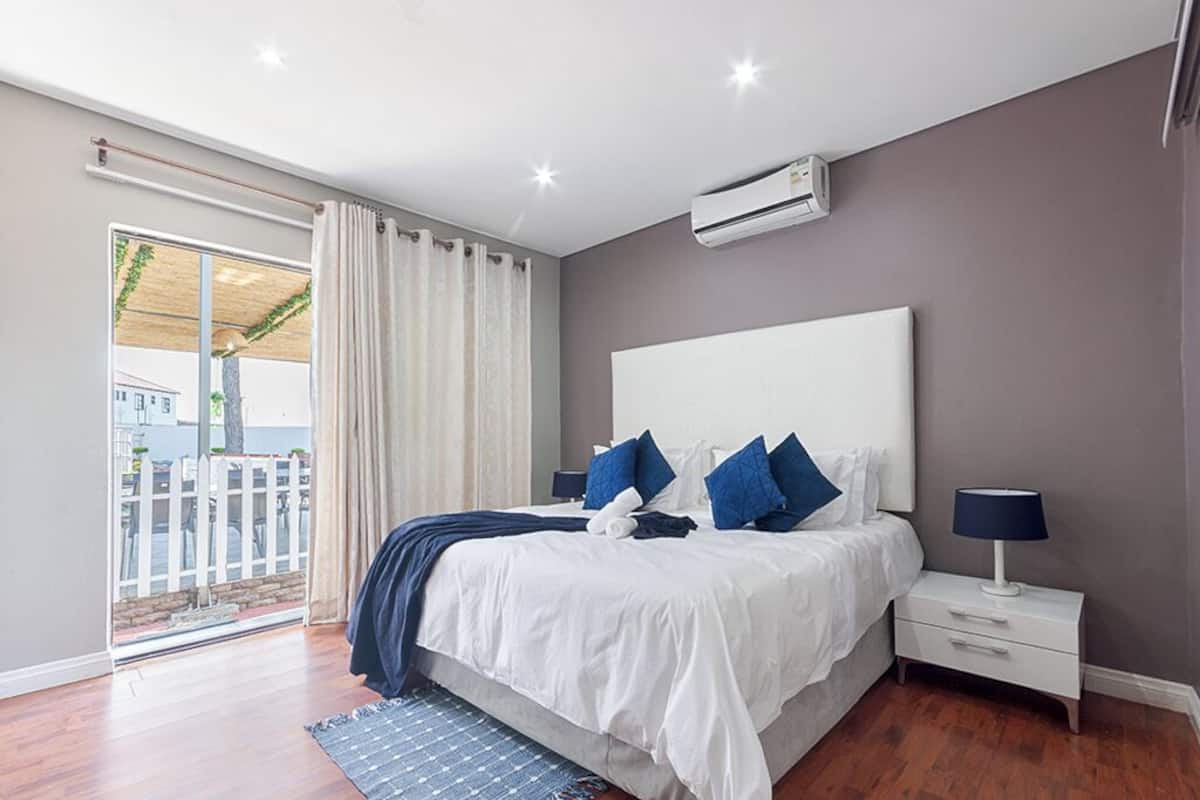 A bedroom with a large bed, a nightstand, a lamp, and a view of the outside.