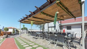 An outdoor patio with tables and chairs, a red pathway, and a white fence. - Botle Ba Afrika Lodge (Vereeniging)