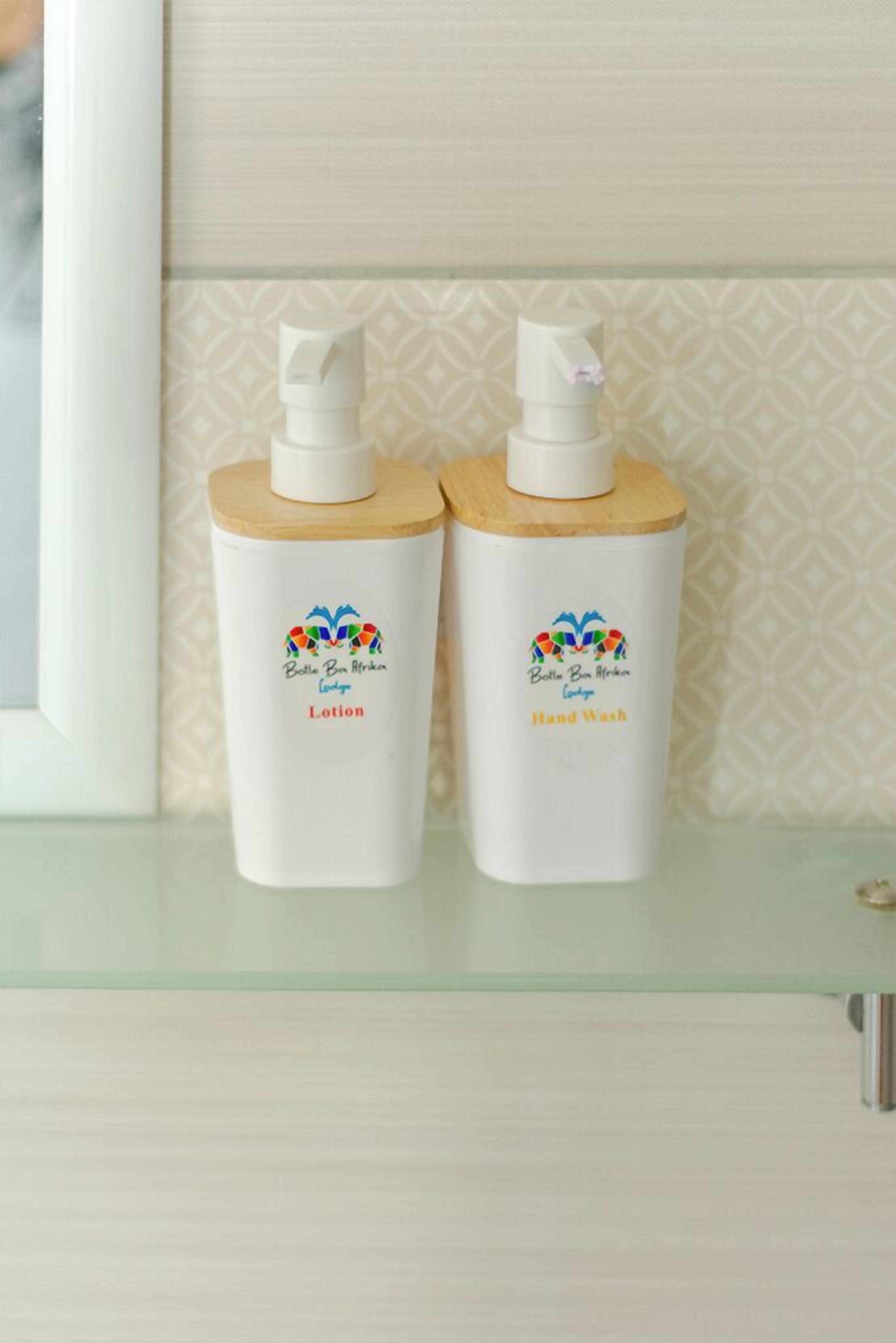 Dos botellas de loción y jabón de manos sobre una estantería de vidrio.